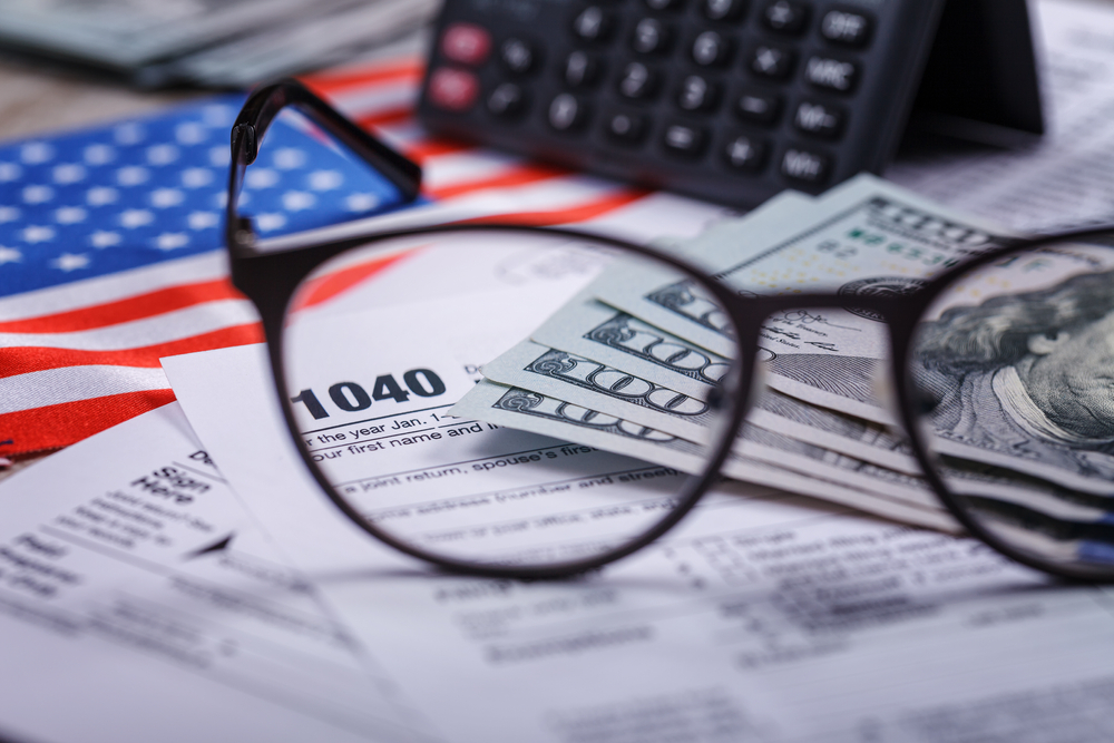 Tax forms, cash, and eyeglasses representing financial planning, tax strategy, and wealth management services USA.